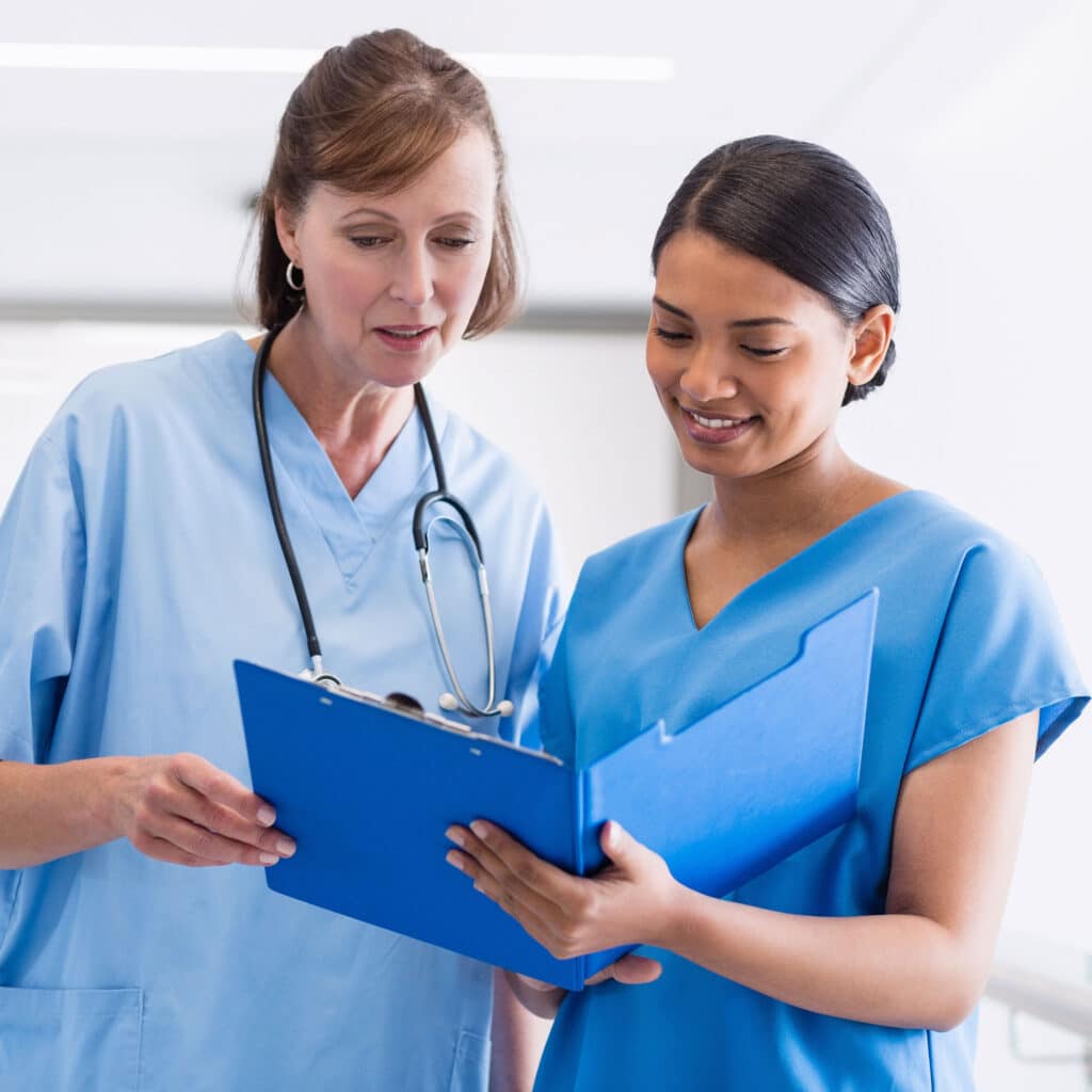 Nurse and doctor discussing over clipboard