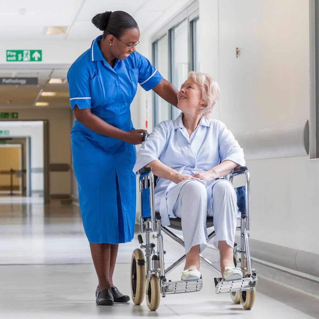 Senior Female Patient in Wheelchair & Nurse in Hospital